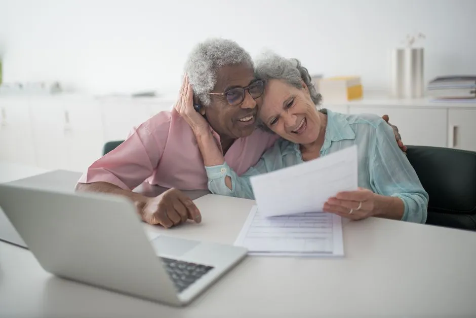 Couple de seniors souriants examinant des documents à son bureau