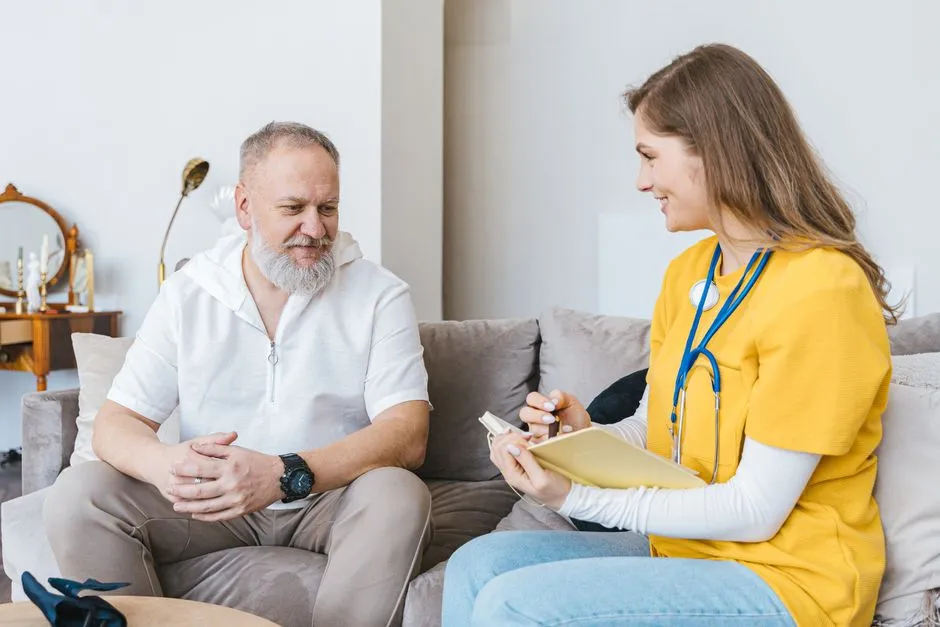 Professionnelle de santé souriante en consultation avec un senior à domicile