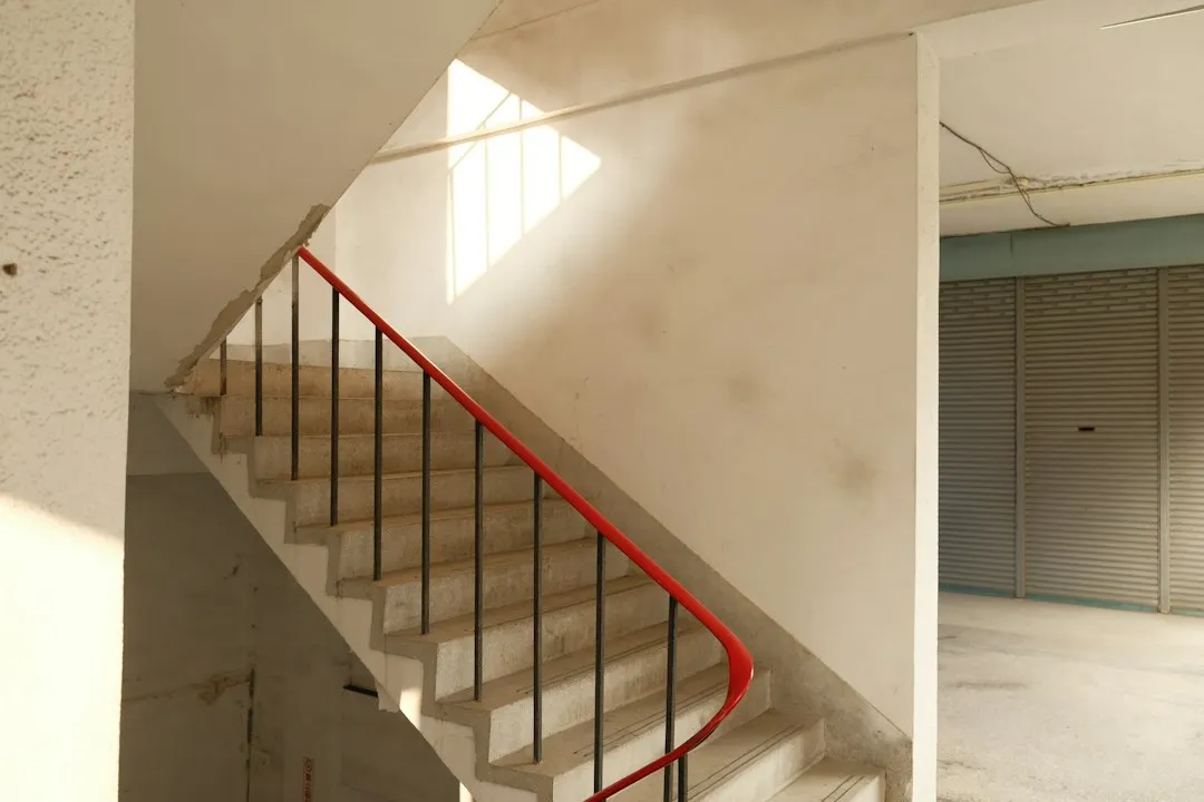 Cage d’escalier tournante à rampe rouge dans un immeuble ancien